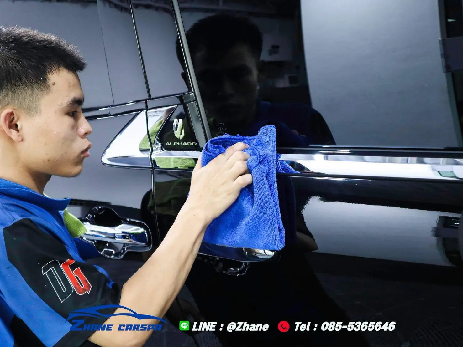 ช่างเช็ดผิวสีประตูรถ Toyota Alphard สีดำด้วยผ้าไมโครไฟเบอร์ เห็นเงาสะท้อนบนผิวสีชัด