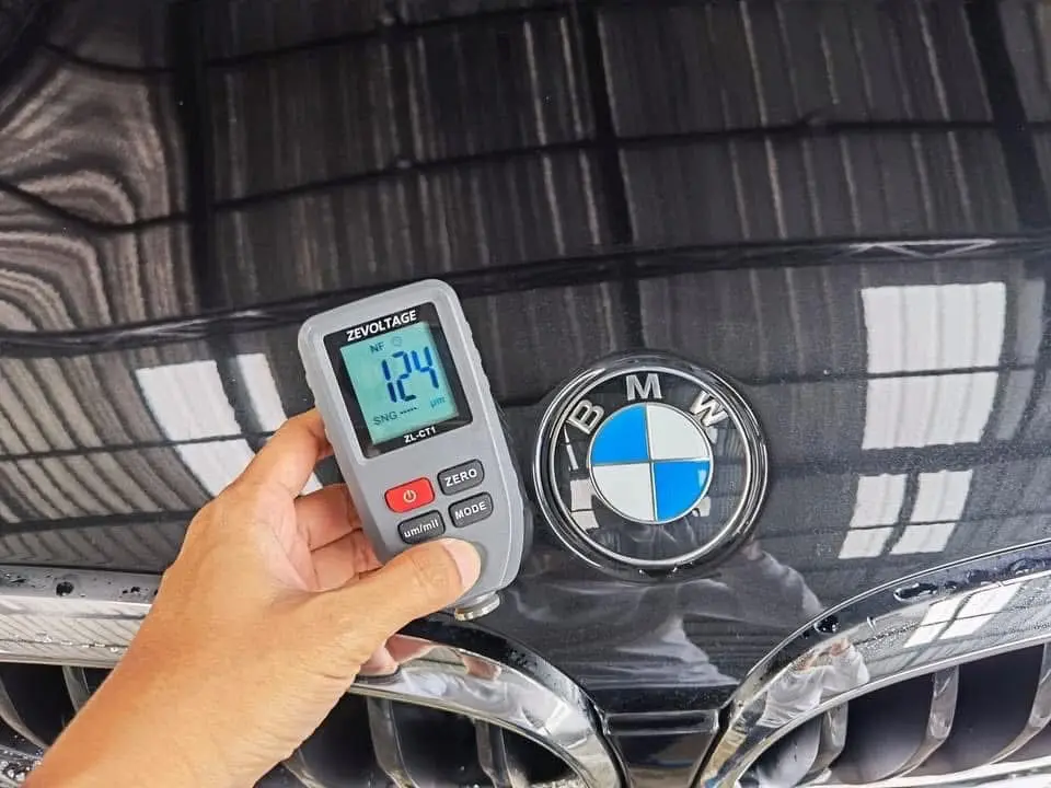 เครื่องวัดความหนาสี ZEVOLTAGE ZL-CT1 แสดงค่า 124 ไมครอน บนฝากระโปรงรถ BMW สีดำข้างโลโก้