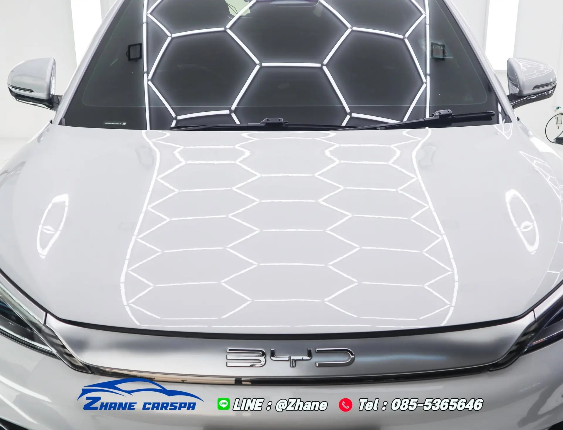 ฝากระโปรงรถ BYD Atto 3 สีขาว แสงไฟรังผึ้งสะท้อนเป็นเส้นเรียบสม่ำเสมอหลังขัดเตรียมผิวและเคลือบเซรามิก