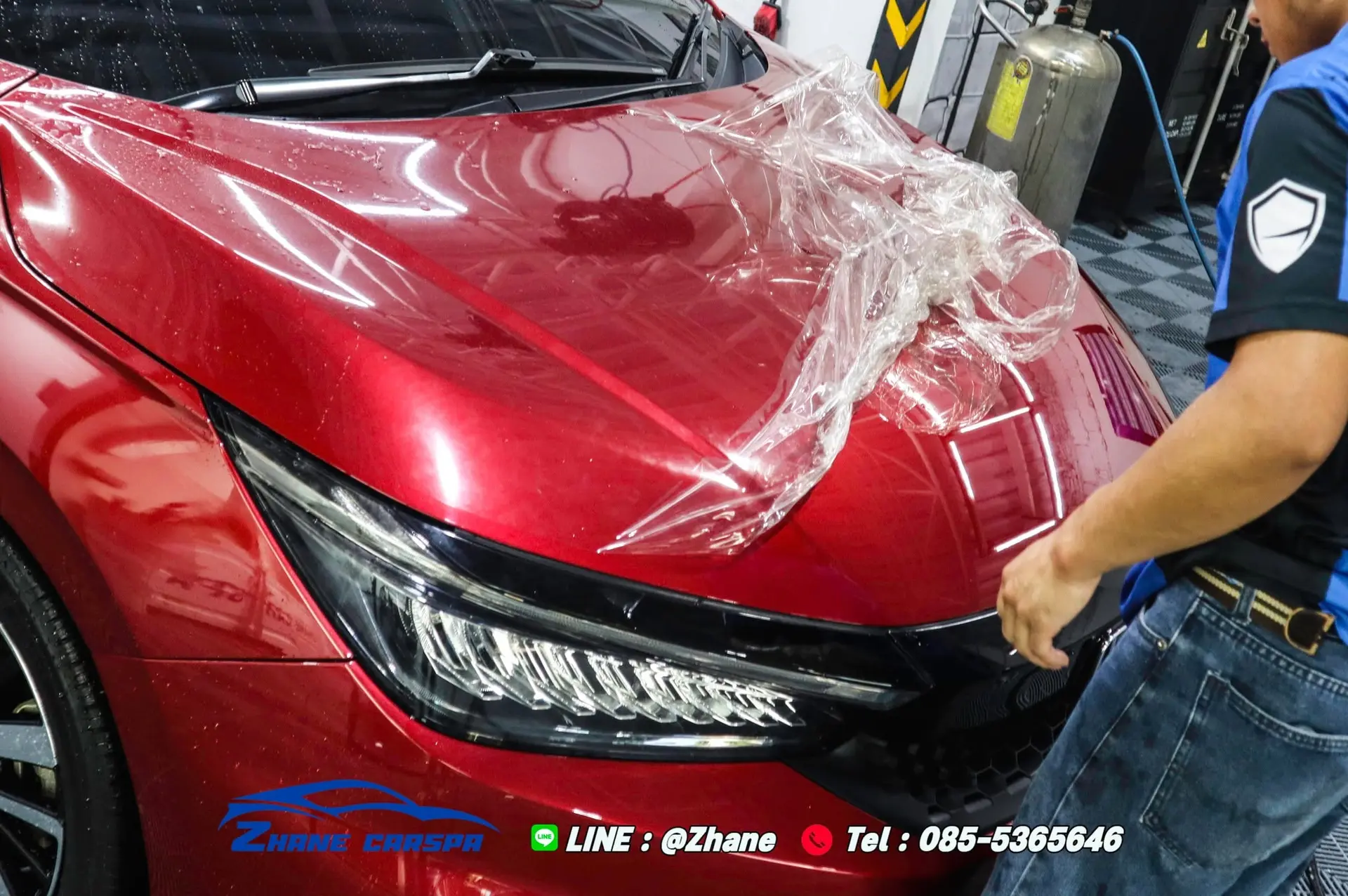 ฝากระโปรง Honda City สีแดงหลังลอกฟิล์มออกบางส่วน มีแผ่นฟิล์มที่ลอกแล้ววางยับอยู่ เทียบผิวสีที่เผยออกมากับบริเวณที่ยังติดฟิล์ม
