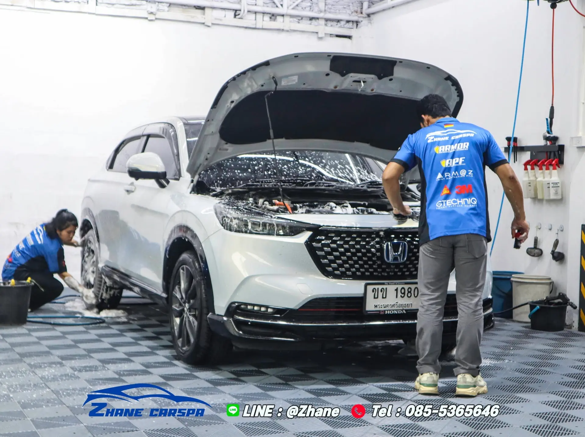 ช่าง Zhane Car Spa สองคนล้างรถ Honda HR-V สีขาวด้วยมือระหว่างเซอร์วิสรอบ 6 เดือน มีฟองแชมพูบนกระจกหน้า ฝากระโปรงเปิดอยู่