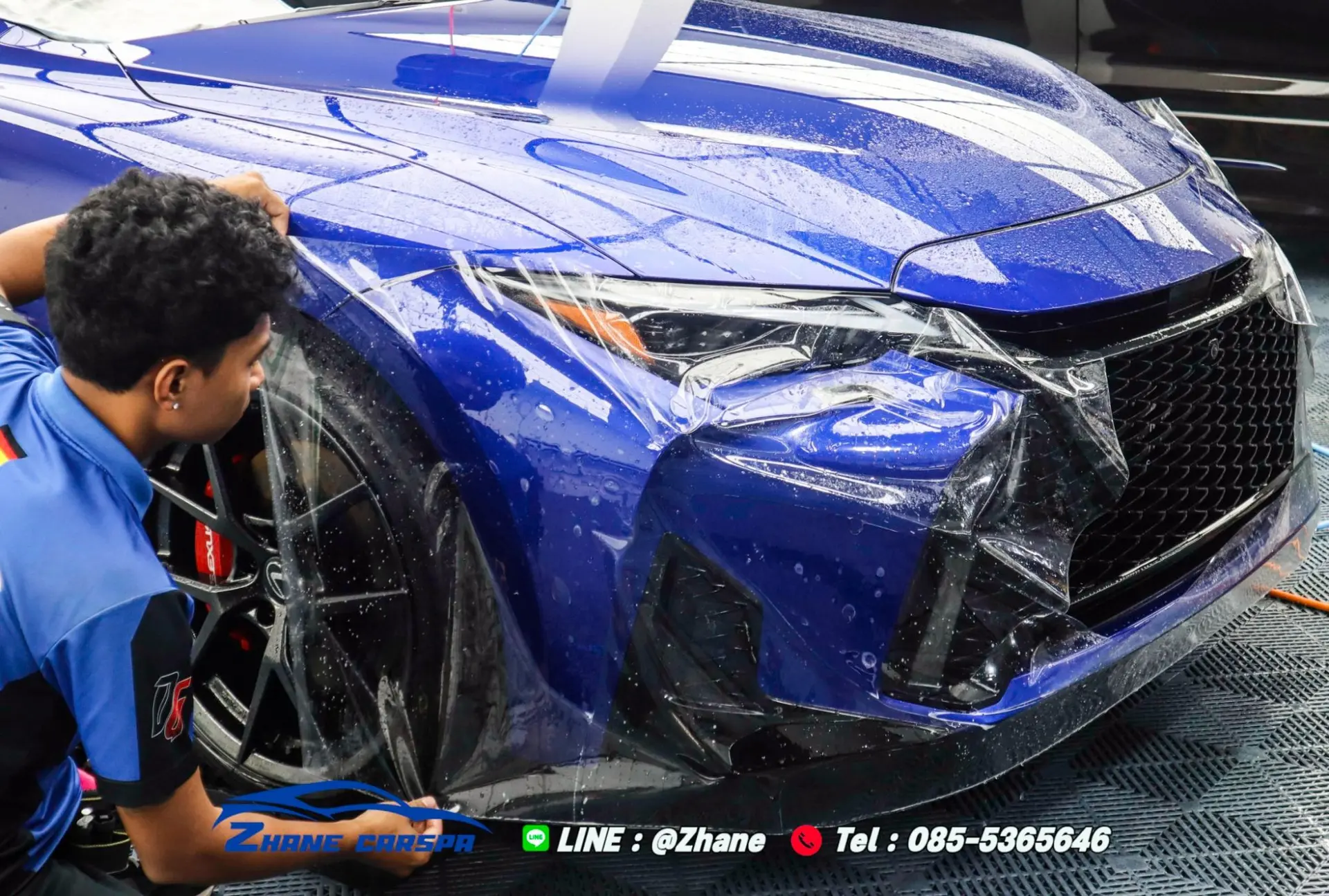 ช่าง Zhane Car Spa กำลังวางฟิล์มใสกันรอยคลุมกันชนหน้า ไฟหน้า และแก้มข้างรถ Lexus สีน้ำเงิน